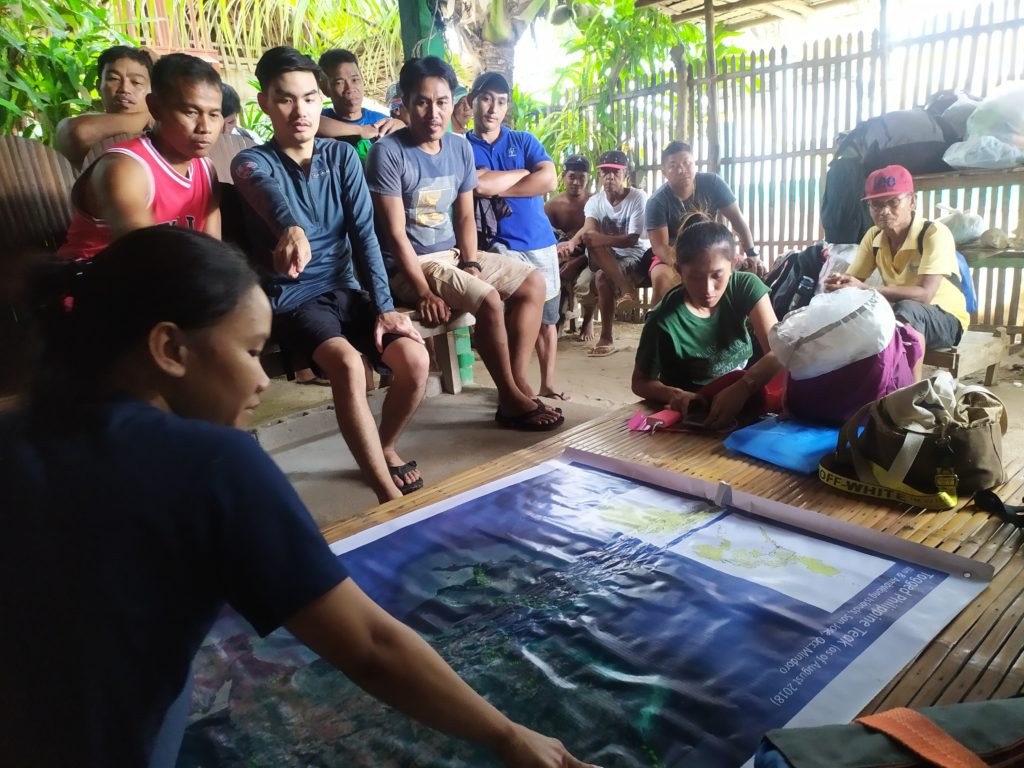 A community meeting with people gathered around a map.